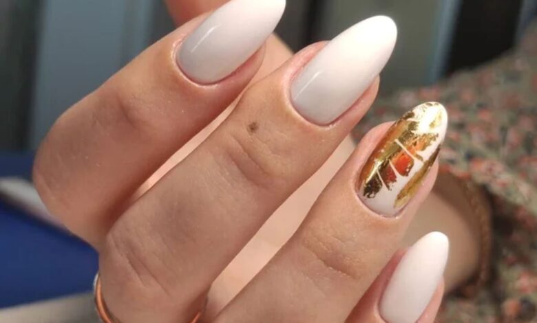 Unhas ovais com esmalte branco e decoração dourada no estilo manicure italian