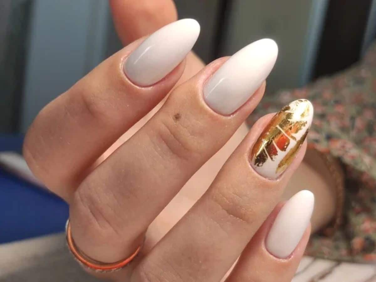 Unhas ovais com esmalte branco e decoração dourada no estilo manicure italian