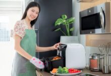 Mulher cozinhando legumes e batatas na air fryer em uma cozinha moderna