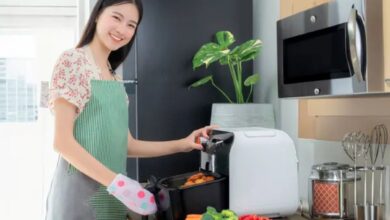 Mulher cozinhando legumes e batatas na air fryer em uma cozinha moderna