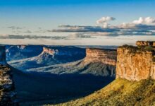 Paisagem da Chapada Diamantina com paredões rochosos e vales cobertos de vegetação ao entardecer.