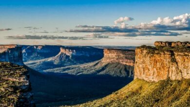 Paisagem da Chapada Diamantina com paredões rochosos e vales cobertos de vegetação ao entardecer.