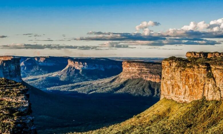 Paisagem da Chapada Diamantina com paredões rochosos e vales cobertos de vegetação ao entardecer.