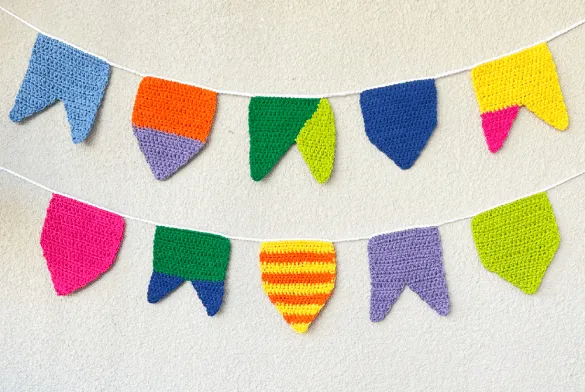 Bandeirinhas de crochê coloridas penduradas em cordão, ideais para decoração de festa junina.