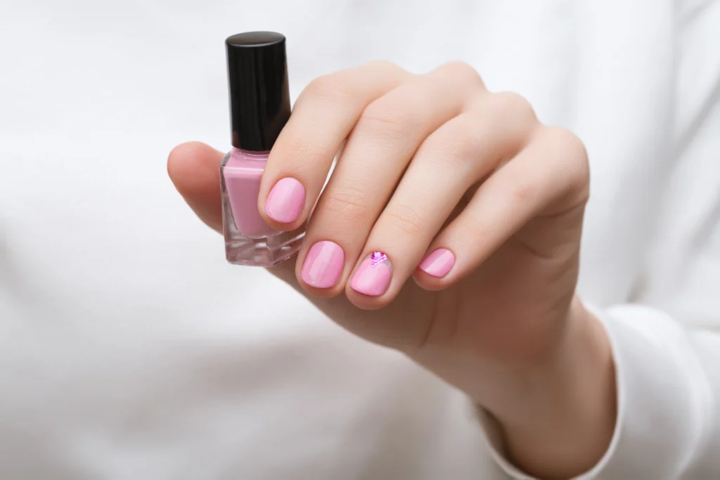 Esmalte rosa suave em unhas de tom de pele oriental com detalhe delicado em strass