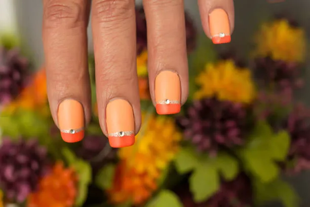 Unhas com esmalte em tons de pêssego e coral, ideal para pele morena