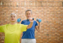 Casal de idosos praticando exercícios com halteres em ambiente fechado