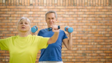 Casal de idosos praticando exercícios com halteres em ambiente fechado