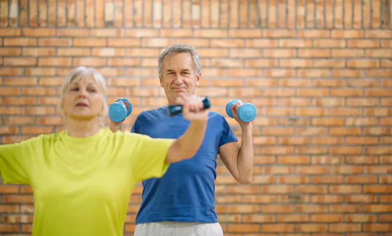 Casal de idosos praticando exercícios com halteres em ambiente fechado