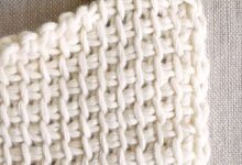 Detalhe de ponto de crochê branco feito à mão com agulha de crochê vermelha.