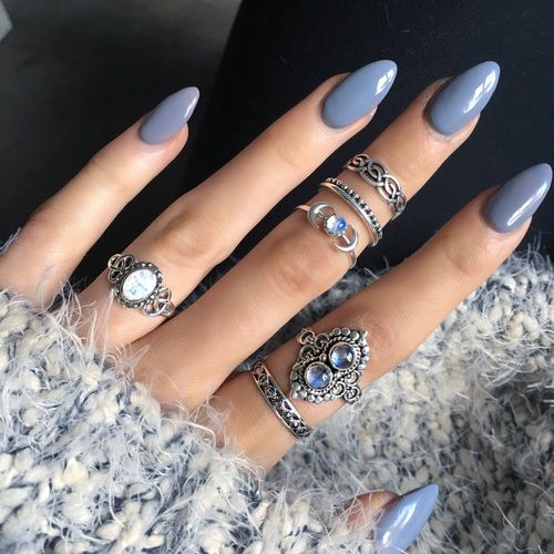 Unhas com esmalte cinza azulado combinadas com anéis prateados