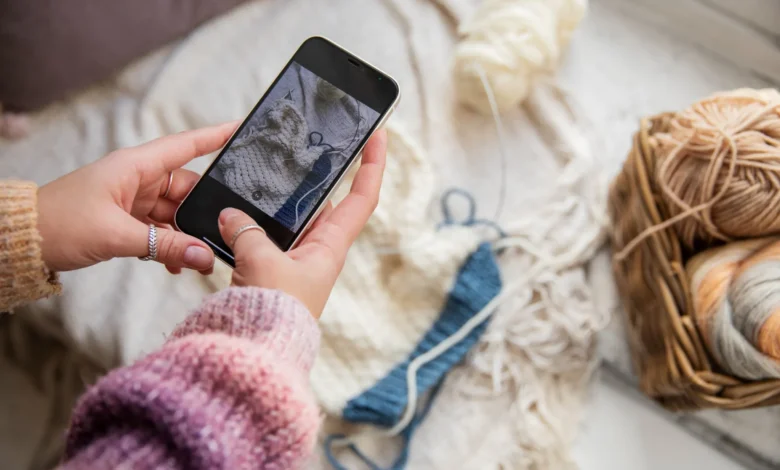 Pessoa fotografando peças de crochĂȘ com o celular para divulgar nas redes sociais
