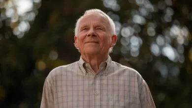 Homem idoso sorrindo, olhando para cima, em ambiente ao ar livre com luz suave