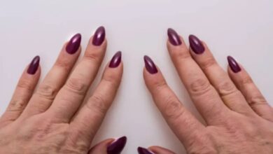 Imagem de mãos femininas com unhas alongadas e decoradas, mostrando as unhas em gel de cor roxa.