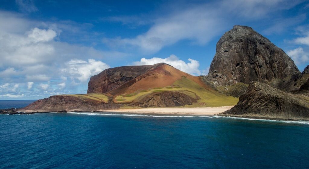 Vista da Ilha de Trindade, com seus imponentes montes e águas cristalinas do oceano Atlântico.
