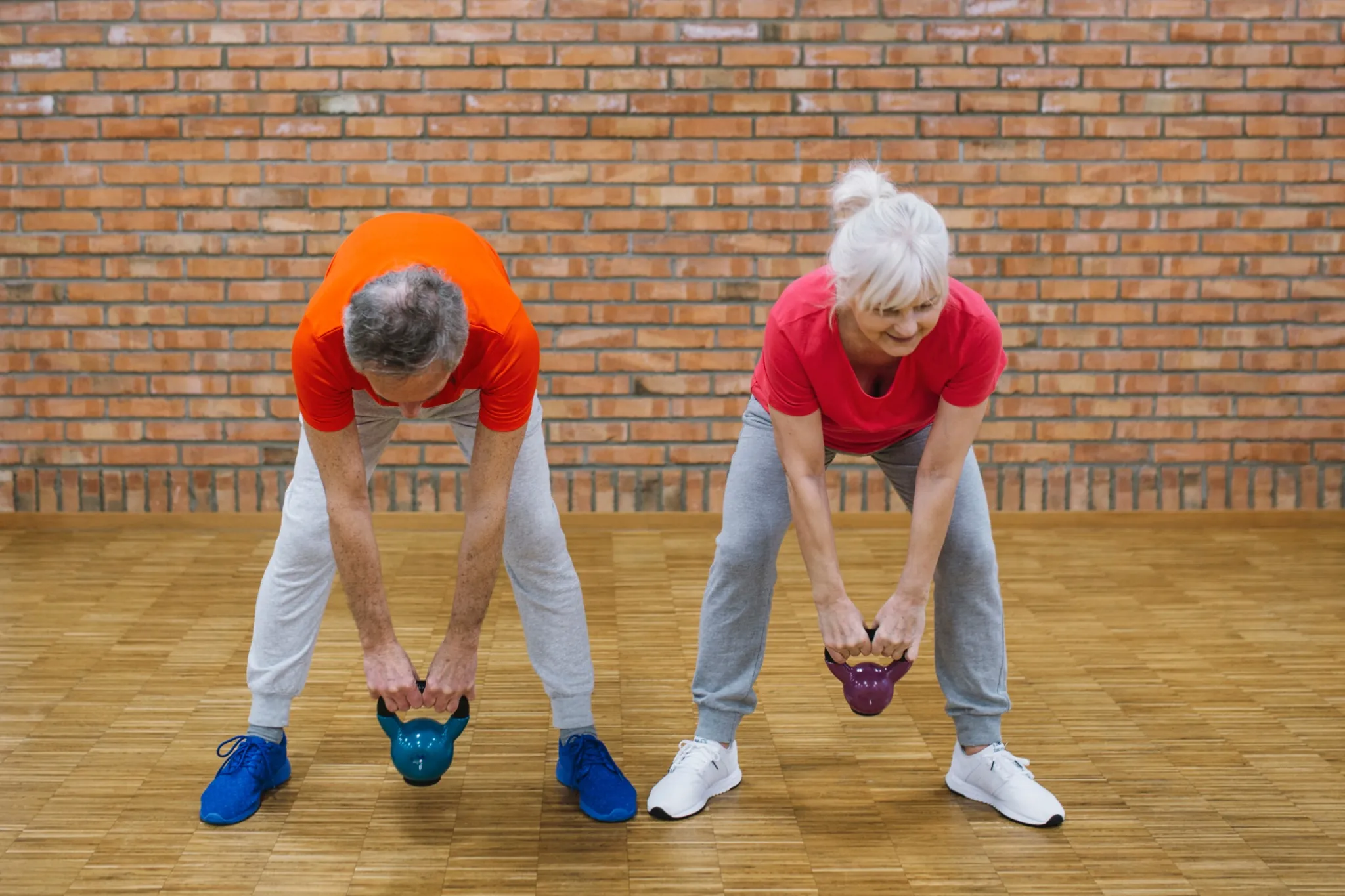 Idosos praticando levantamento de peso com kettlebell em ambiente interno