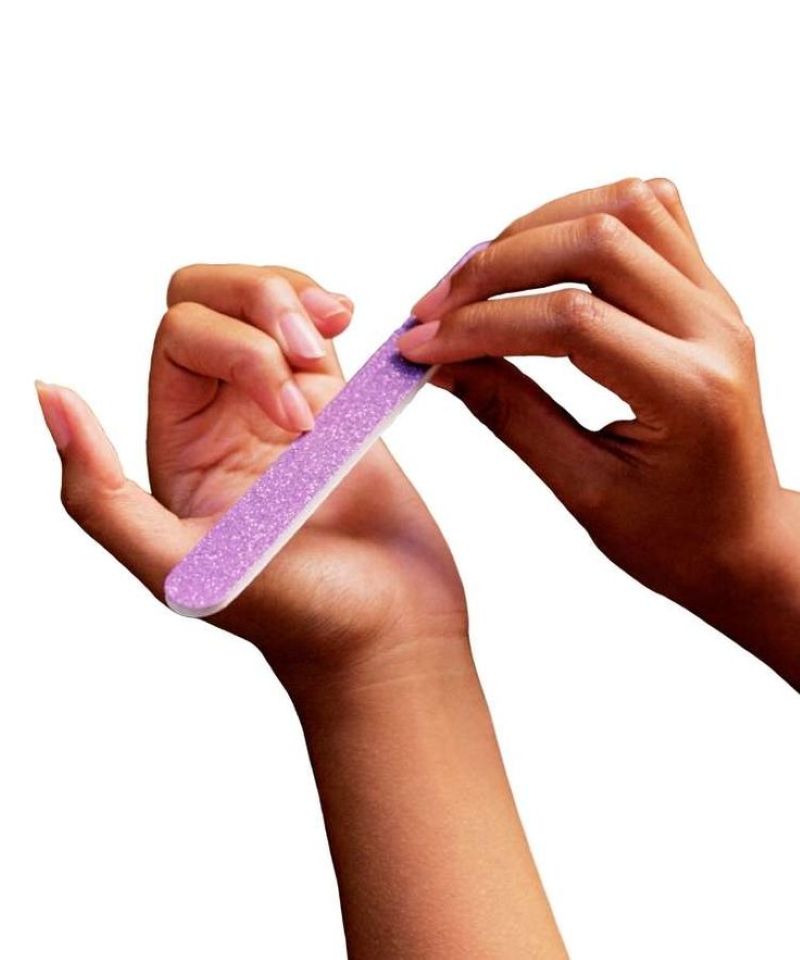 Pessoa lixando as unhas com lixa roxa para manter o formato e evitar quebras
