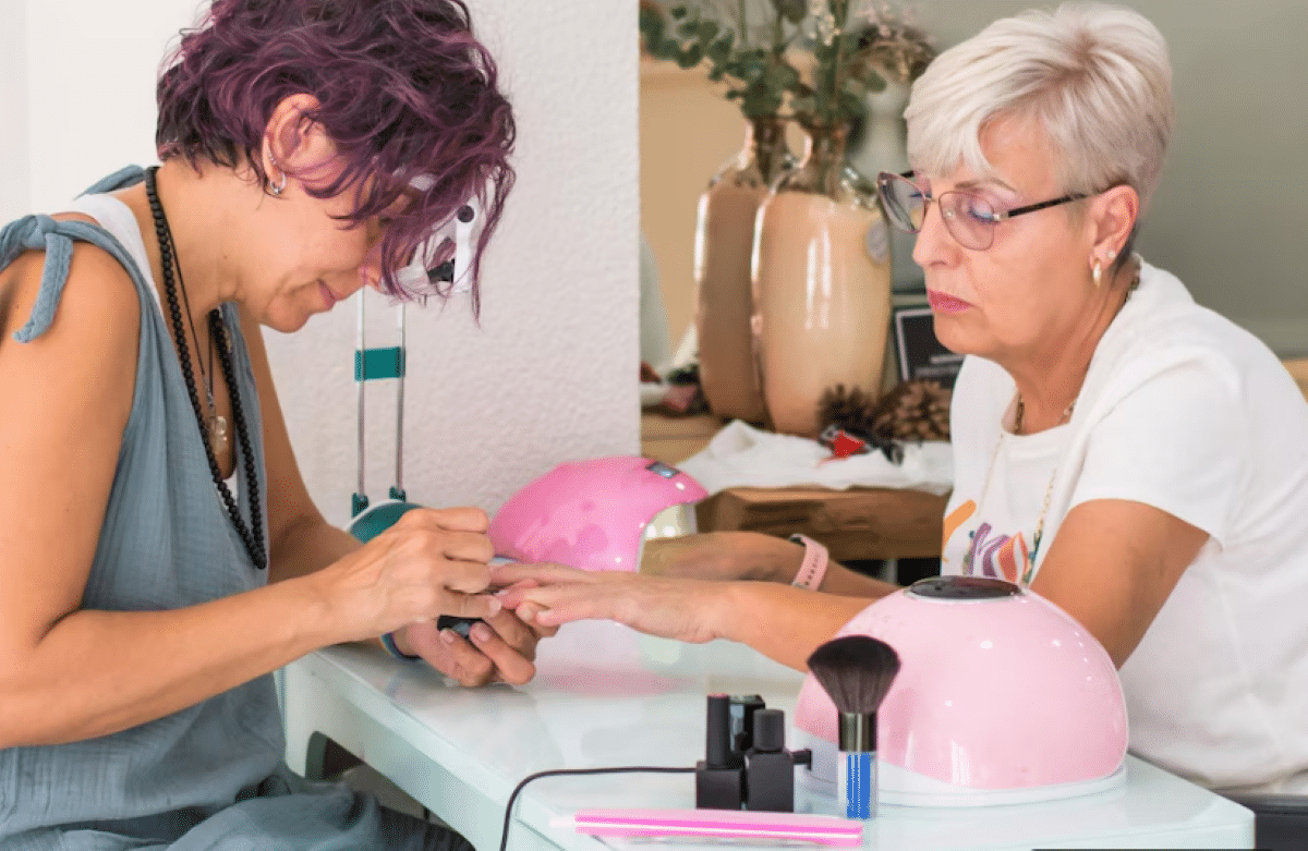 Mulher madura cuidando das unhas em salão de beleza com manicure profissional