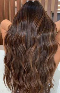 Cabelos longos com mechas caramelo realçando tons quentes e naturais.