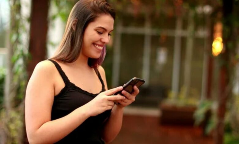 Mulher feliz lendo mensagem de fim de semana no celular ao ar livre