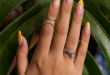 Unhas com francesinha moderna em amarelo vibrante com fundo de folhas verdes tropicais.