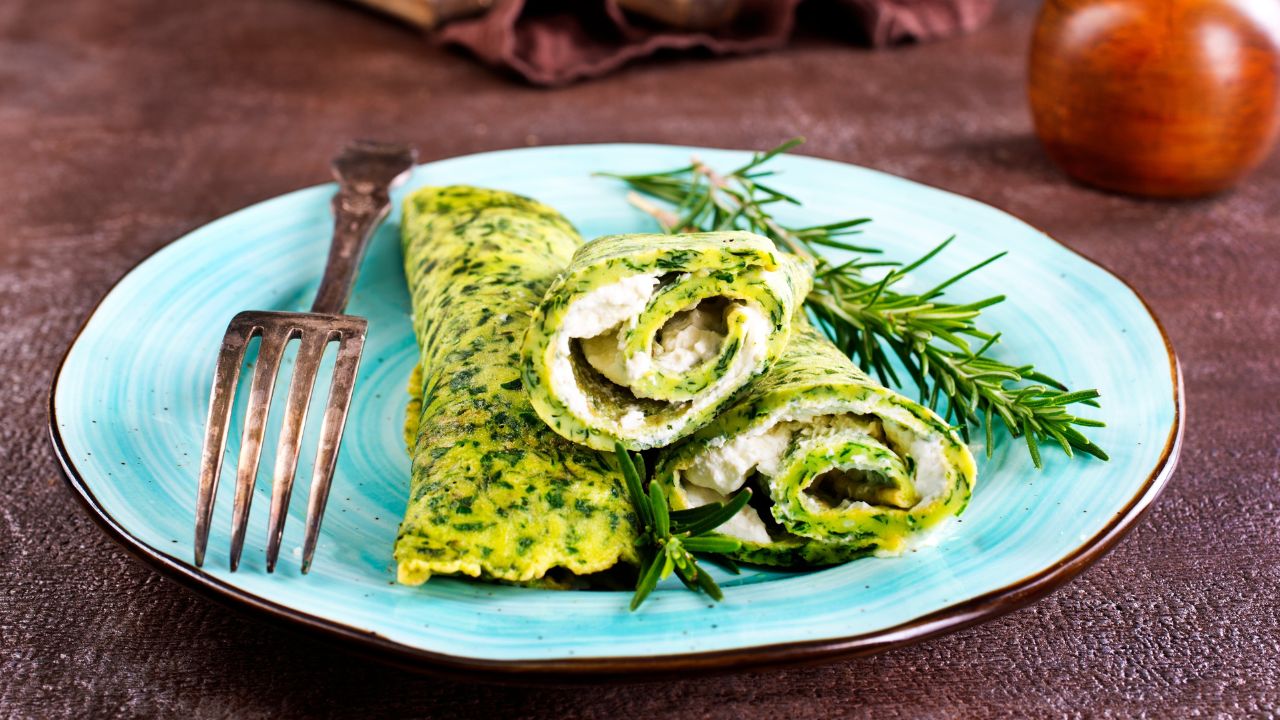 Panquecas verdes com recheio cremoso de queijo e espinafre em prato azul