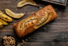 Pão de banana caseiro com bananas maduras e nozes sobre mesa rústica de madeira