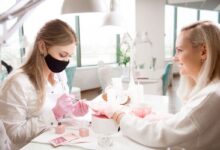 Profissional fazendo manicure com esmalte em tons terrosos em cliente no salão de beleza