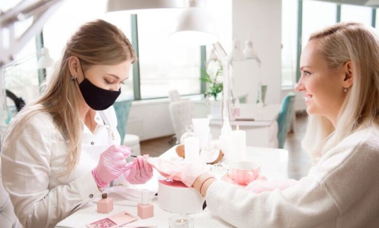 Profissional fazendo manicure com esmalte em tons terrosos em cliente no salão de beleza