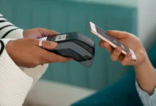 Pessoa utilizando o Pix por aproximação com tecnologia NFC para realizar um pagamento no restaurante, segurando o celular perto da maquininha de cartão.