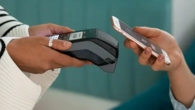 Pessoa utilizando o Pix por aproximação com tecnologia NFC para realizar um pagamento no restaurante, segurando o celular perto da maquininha de cartão.