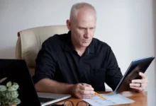 Homem concentrado analisando documentos financeiros com laptop ao lado, simbolizando planejamento financeiro para aposentados em 2025.