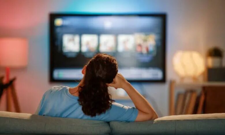 Mulher assistindo novelas turcas em plataformas de streaming na televisão em casa