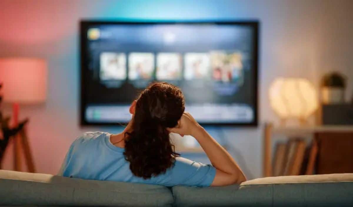 Mulher assistindo novelas turcas em plataformas de streaming na televisão em casa