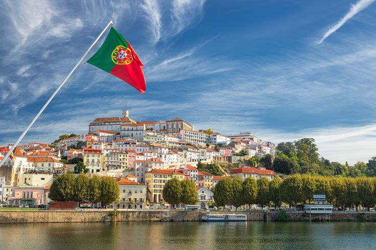 Vista panorâmica de cidade portuguesa com casas antigas e bandeira de Portugal ao vento