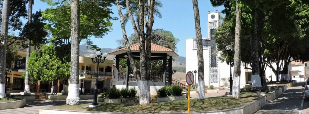 Praça central de Córrego do Bom Jesus–MG, com coreto e igreja ao fundo em dia ensolarado