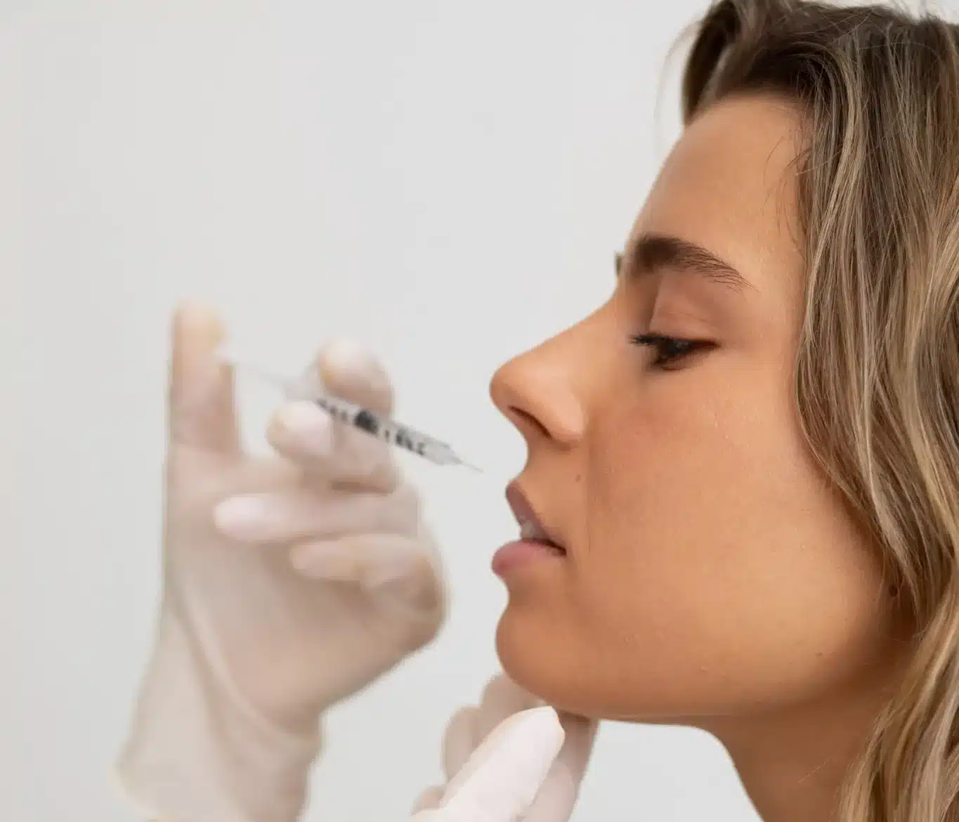 Mulher recebendo preenchimento labial com procedimento estético de injeção