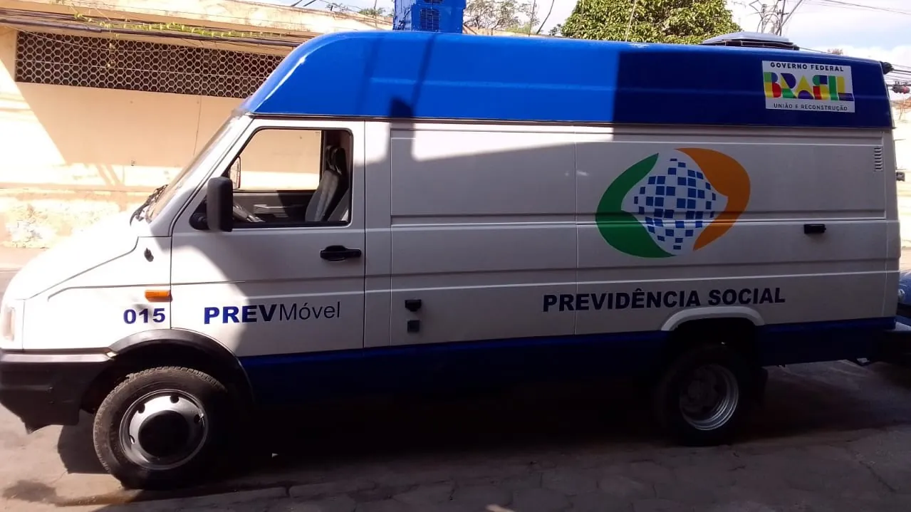Van branca e azul do PrevMóvel da Previdência Social estacionada, veículo móvel de atendimento social.