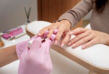 Profissional aplicando esmalte em unhas perfeitas durante um processo de manicure.