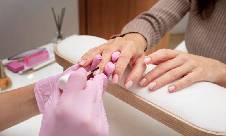 Profissional aplicando esmalte em unhas perfeitas durante um processo de manicure.