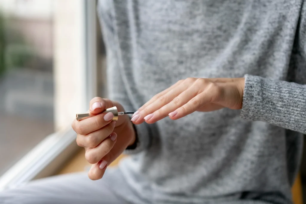 Uma pessoa aplicando um produto fortalecedor de unhas durante o processo de manicure, com foco em unhas naturais e saudáveis.