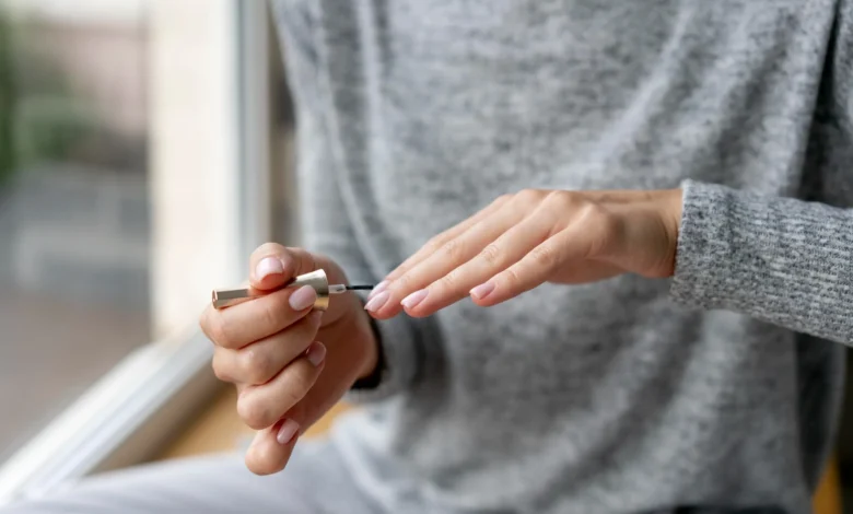 Uma pessoa aplicando um produto fortalecedor de unhas durante o processo de manicure, com foco em unhas naturais e saudáveis.