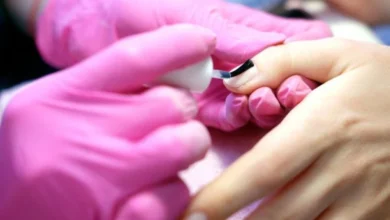 Aplicação de esmalte em gel em unha com profissional usando luvas rosas