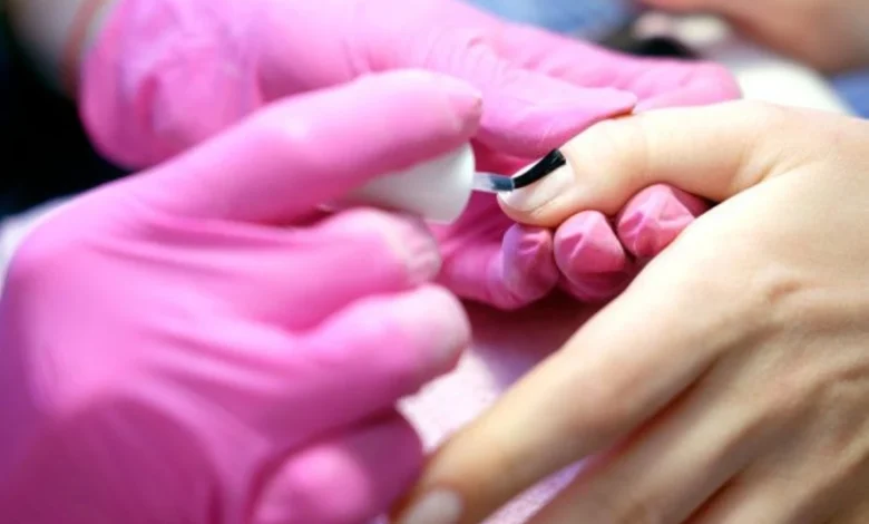 Aplicação de esmalte em gel em unha com profissional usando luvas rosas