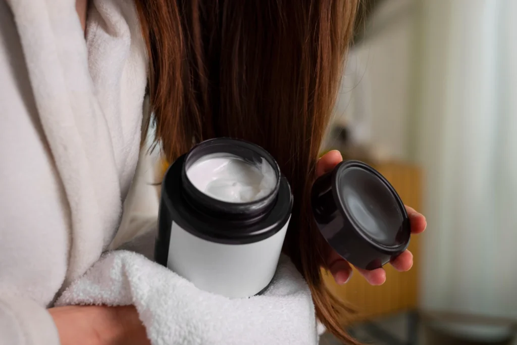 Mulher segurando pote de creme para reconstrução capilar, cabelo danificado e tratamento com queratina.