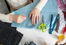 Pessoa traçando molde em tecido azul durante processo de customização de roupas.