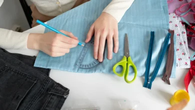 Pessoa traçando molde em tecido azul durante processo de customização de roupas.
