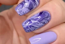 Unhas decoradas com efeito marmorizado nas cores roxas, ilustrando o tutorial de como fazer esse tipo de decoração.