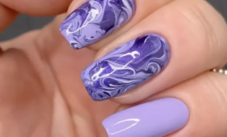 Unhas decoradas com efeito marmorizado nas cores roxas, ilustrando o tutorial de como fazer esse tipo de decoração.
