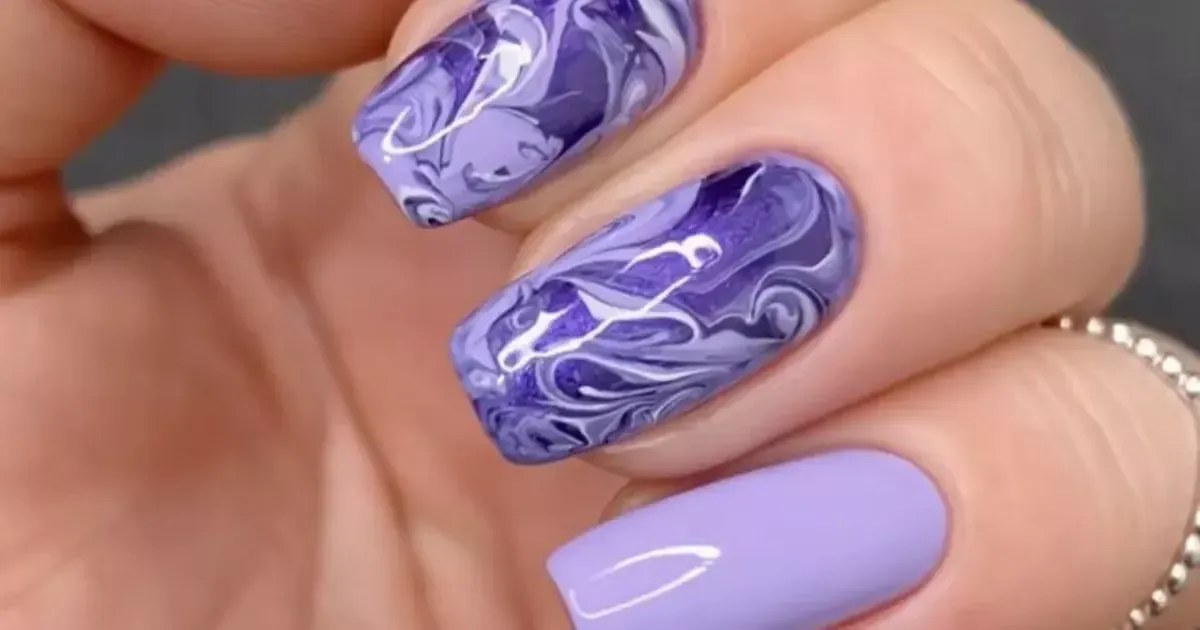 Unhas decoradas com efeito marmorizado nas cores roxas, ilustrando o tutorial de como fazer esse tipo de decoração.